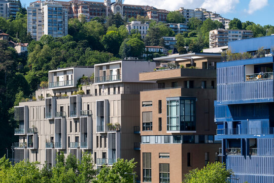 Residential buildings in La Confluence district, Lyon, layer apartments, facades, balconies, hillside greenery and urban housing density in daylight