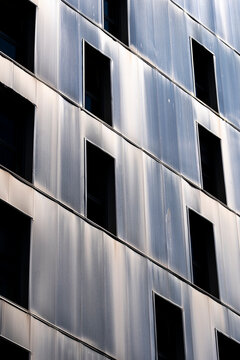 Reflective facade windows on apartment building in La Confluence district, Lyon, reveal metal panels, shadow, vertical pattern and urban housing texture