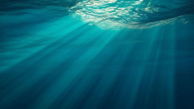 Underwater ocean surface with shimmering light rays piercing through deep blue water in motion video clip