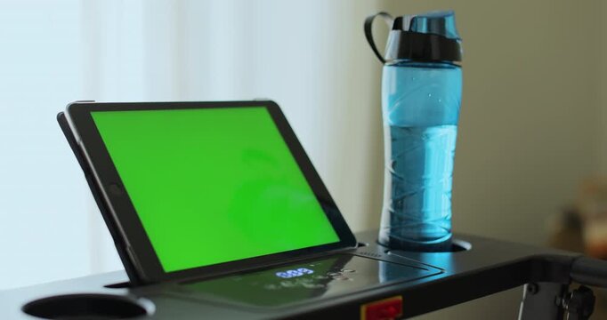 Back view. Fitness, girl and walking on treadmill in home for cardio exercise, wellness challenge and burning calories. Tablet with green screen.