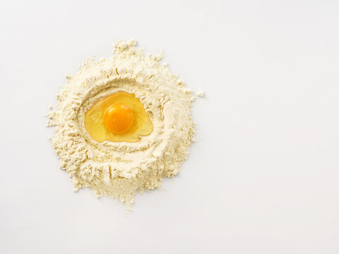 Fresh egg in a well of flour, perfect for baking or recipe development, cooking class, and culinary preparation