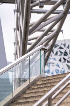 Concrete stairs rise beside glass and structure, where exterior urban steps, architecture, geometry and handrail frame a precise ascent