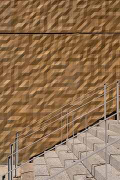 Sunlight crosses stairs beside a facade, where architecture, concrete, handrail and pattern turn exterior urban steps into geometry on a quiet surface