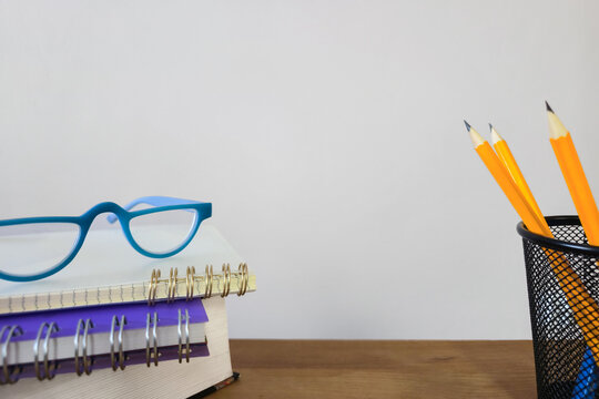 Education and work concept with stationery on desk. Flat lay composition of notebooks, books, glasses, pens and pencils around white paper with copy space. Study, office, learning and background