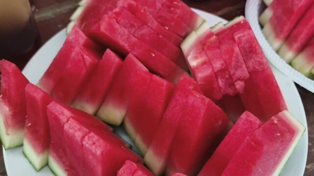 Cinematic extreme close up of freshly sliced juicy red watermelon pieces arranged in rows, showing vibrant organic texture and sweet watery pulp details.