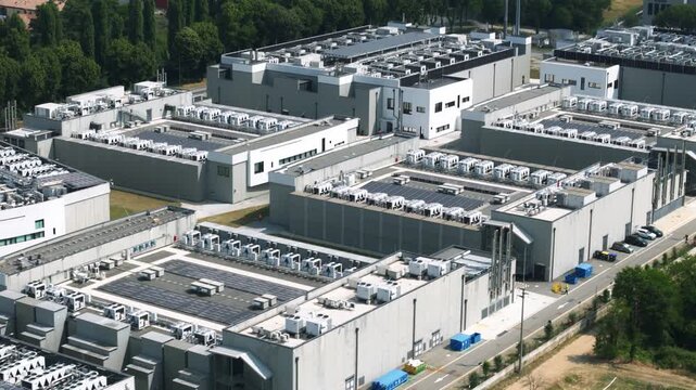 Aerial footage of a large-scale data center complex featuring multiple buildings with rooftop cooling systems and solar panels for sustainability