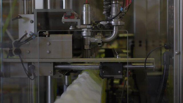 Industrial machine fills coolant containers on a stainless steel factory production line.