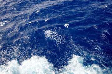 Dark blue ocean water surface background with white foam waves © 2xwilfinger