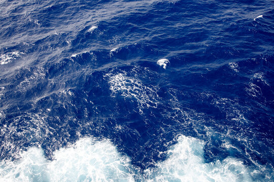 Dark blue ocean water surface background with white foam waves