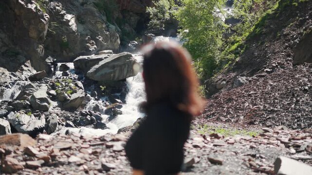 4K shot of defocused girl standing against waterfall in Pangi Valley, Himachal Valley, India. Beautiful waterfall cascade during summer season. Travel and vacation concept.