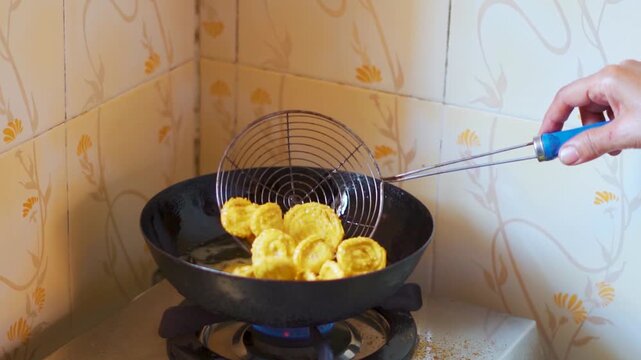 Close-up shot of traditional Indian snacks being deep-fried in hot oil at a home. Crispy chakri cooking in a iron pan. Food preparation in India during festivals. Fried unhealthy food. Indian snacks. 