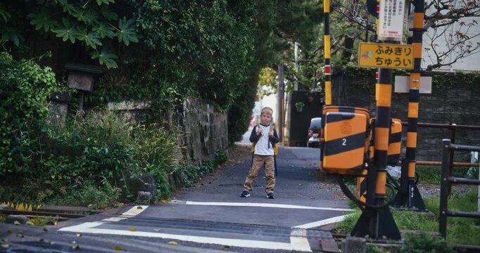 Boy with backpack standing near tracks in small Japanese town