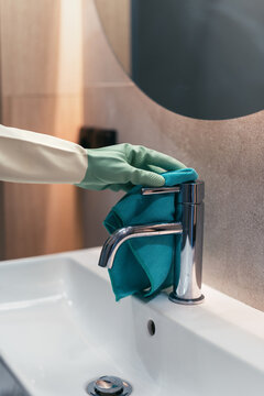 Woman cleans bathroom faucet in a modern apartment setting