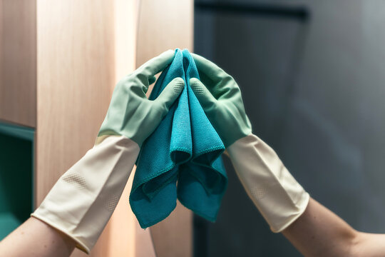 Woman in gloves cleans bathroom mirror in modern apartment