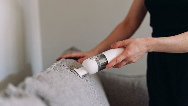 Woman uses small cordless vacuum cleaner for house cleaning tasks