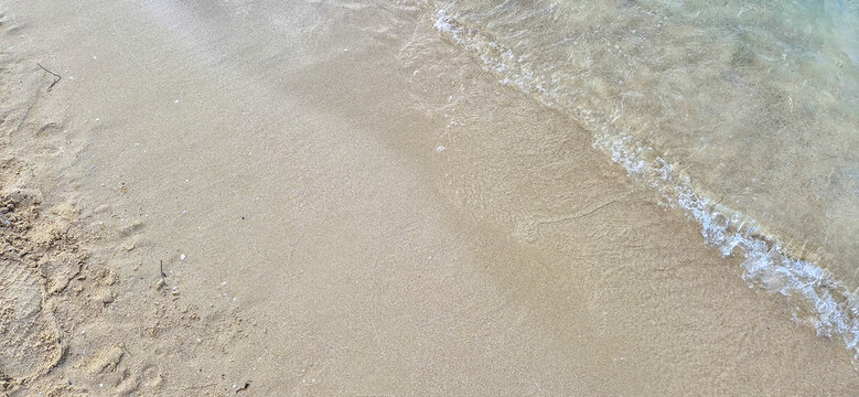 Clear shallow sea wave washing over wet sandy beach