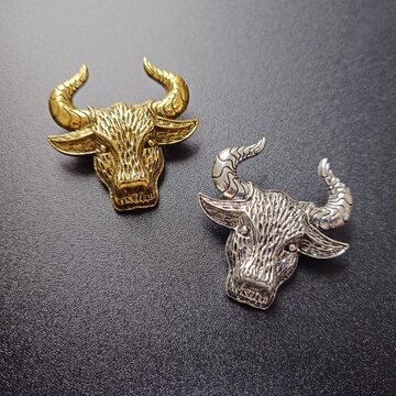 Gold and Silver Bull Pins Placed on Leather Texture