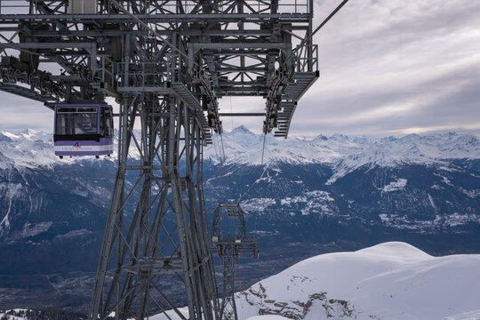 Crans-Montana, Switzerland - February 1, 2026: Panoramic view from Funitel Violettes-Plaine Morte with aerial lift pylon over Rhone Valley towards Val d'Anniviers against cloudy skys