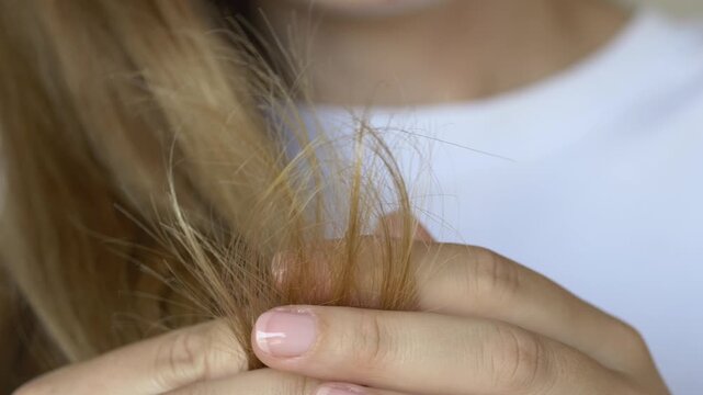Woman holds and examines hair ends checking for split ends and damage in daily haircare concern routine closeup. Footage for hair treatment brand promotion, trichology clinic content, haircare beauty