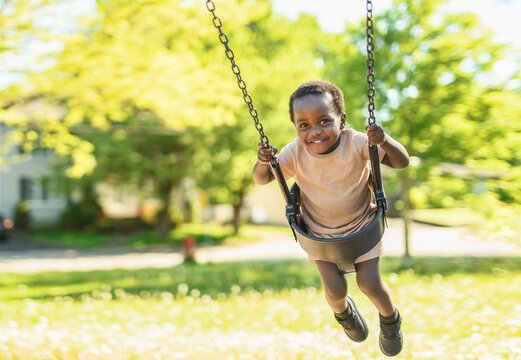 Happy young american child on playground swing this summer season