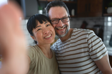 Fototapeta premium Affectionate multicultural couple enjoying a playful moment together at home. Warm embrace and genuine smiles convey love, trust, companionship and emotional connection in everyday life