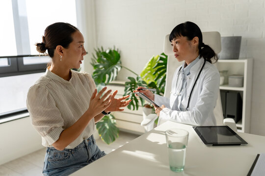Professional physician explaining health concerns to patient across office desk. Medical guidance, active listening, trust and collaborative healthcare decision making