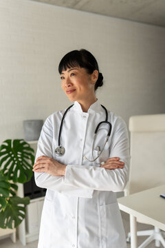 Professional female doctor standing confidently in bright clinic. Medical career, healthcare workforce, leadership and modern healthcare concept