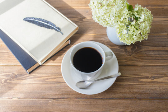 Coffee and books with Annabelle hydrangea on a wooden table