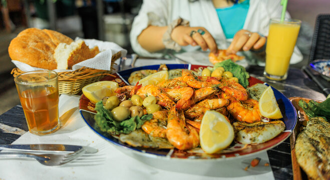 a plate of moroccan style BBQ seafood with lemon, mint tea and bread