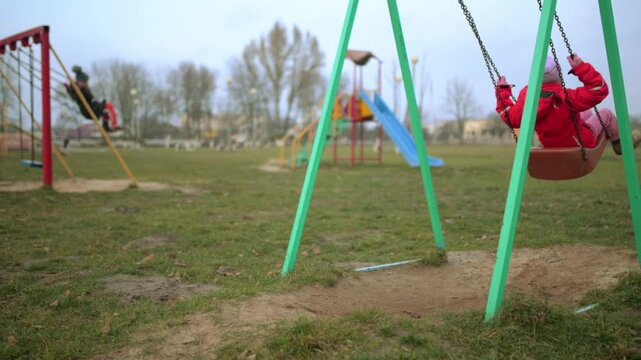 Two beautiful little girls on swing in autumn park