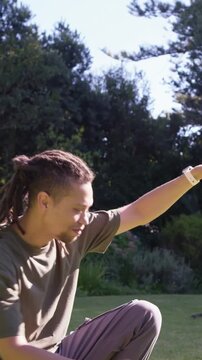 Vertical video: Reacting to offscreen cue, man in green T gesturing fixing hair at park, copy space