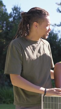 Vertical video: Pointing, man-olive-tee showing solar panel in garden to woman-yellow-top, hugging