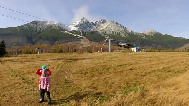 Two little sisters and their mother walk during a strong wind near Lomnicky stit, High Tatras, Slovakia.