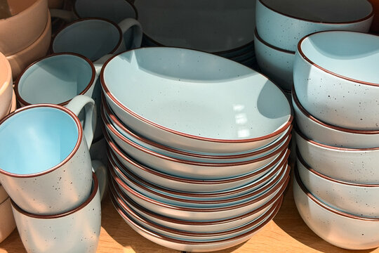 Light blue speckled ceramic dishes and mugs stacked on display shelf