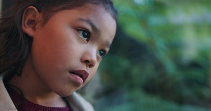 Thinking, sad and kid by window in home with reflection of trauma, bad memory and loneliness. Apartment, space and child with thoughts, sigh and upset emotions for separation, alone and worry