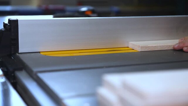 Circular table saw cutting wood in carpenter workshop close up. A running blade on a bench saw sawing trough the wooden log in the middle of a working space, close up footage. A sawing circle that cut