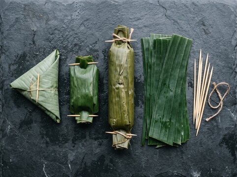 Traditional Indonesian Food Wrapping Techniques with Banana Leaves on Dark Stone