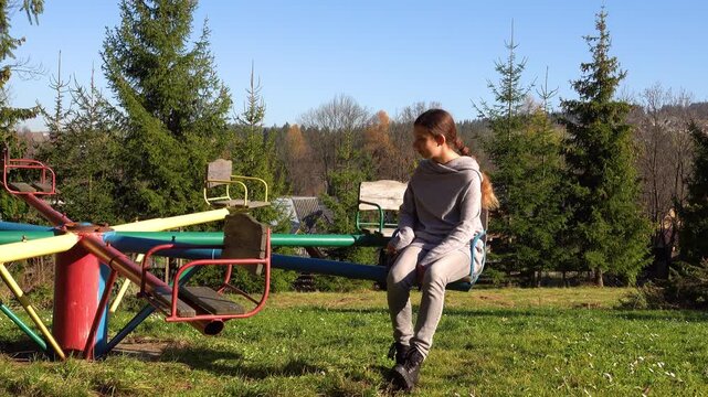 Two beautiful girls ride on a circular carousel In the autumn park