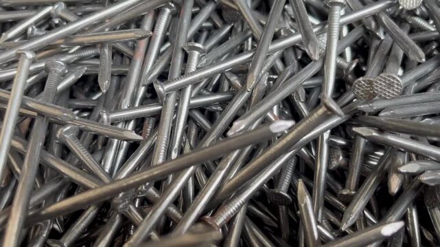 A messy heap of shiny steel wire nails for woodworking. Macrophotography of industrial fasteners and metal hardware equipment 