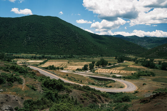 scenic SH75 road winding through dense pine forests and mountain valleys near a lake in Albania. Picturesque Balkan countryside