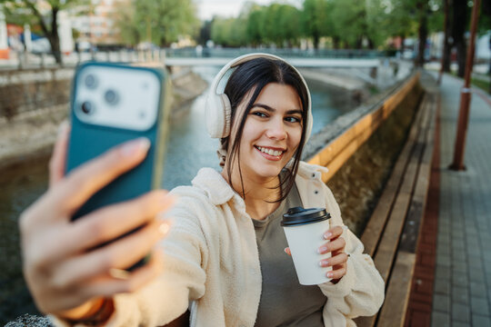 Happy woman recording a video with smartphone in city