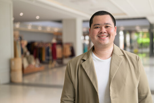 Smiling plus size Isan Thai man in shopping mall horizontal