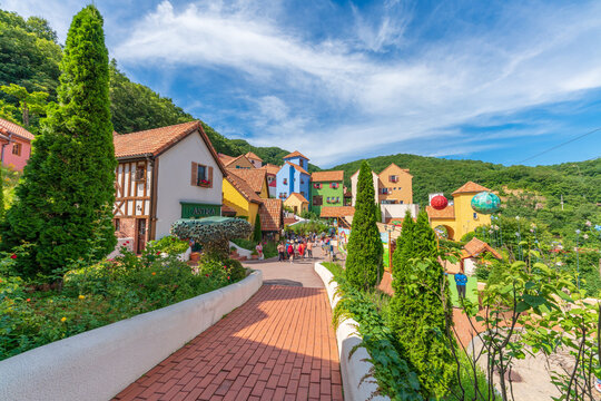 Scenic perspective of Petite France theme park featuring vibrant pastel buildings and French traditional architecture surrounded by green mountains, landmark in Gapyeong, Republic of Korea.