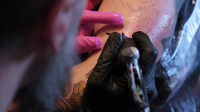 Tattoo artist applies ink on the arm in a studio while ensuring safety and cleanliness during the process