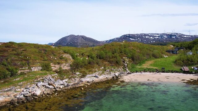 Aerial of small traditional village with greenery covered mountain background, on summer Sommaroy island, Norway