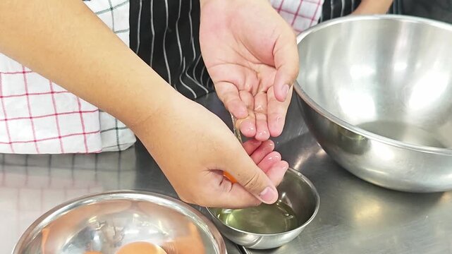 Chef separating egg yolk from white by hand.