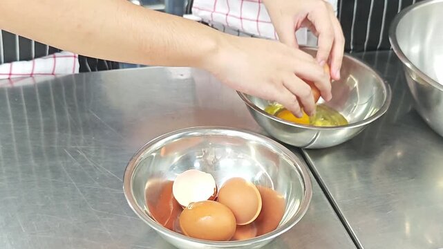 Chef hands cracking a fresh brown egg into a mixing bowl.