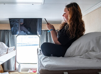 Fototapeta premium An 11-year-old Caucasian girl uses a cell phone in a cruise ship cabin.