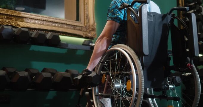 Man in wheelchair performing dumbbell bicep exercises in gym. Adaptive fitness, strength training, determination and active lifestyle concept.