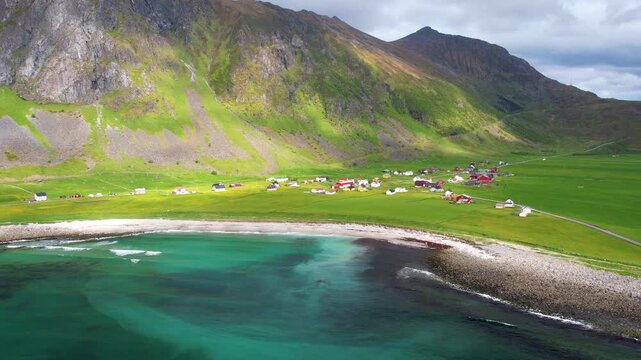 Aerial drone view of Lofoten Islands in Norway, featuring beautiful landscapes on Unstad Beach, white sand, clear water and dramatic mountains near the shore. Experience the natural beauty